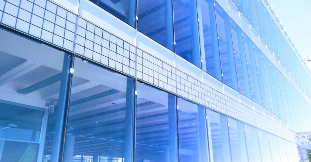 Contemporary glass building facade with reflections in the city, highlighting urban architecture.